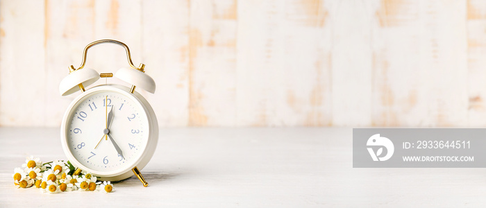 Banner with alarm clock and flowers on table. Spring time