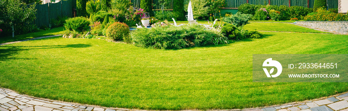 Beautiful manicured lawn and flowerbed with deciduous shrubs on plot or Park outdoor. Green lawn closely mowed grass.