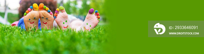 Children’s feet with a pattern of paints smile on the green grass. Selective focus.