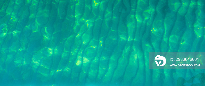 Green abstract texture background of emerald green sea water. Top view of green sea water with unique pattern. Green background. Sea water wave surface at coast. Turquoise water at shallow sea.