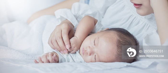 Portrait of beautiful young asian mother with her newborn baby hands holding, copy space with bed in the hospital. Healthcare and medical family love lifestyle nursery together mother’s day