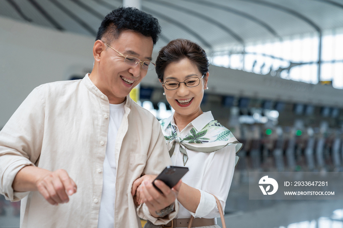 快乐的老年夫妇在机场使用手机