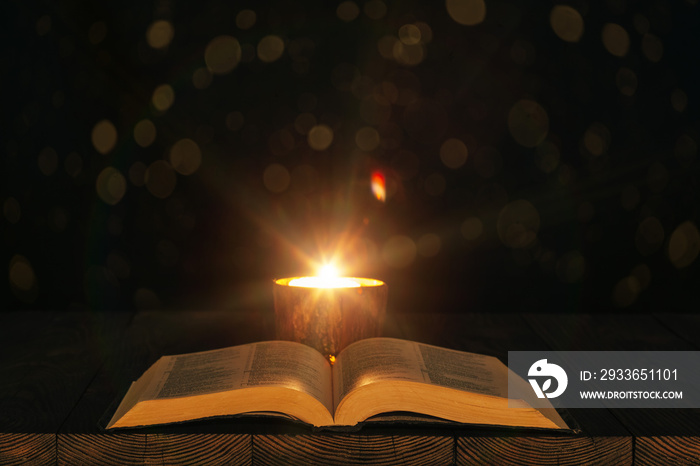 bible on the table in the light of a candle