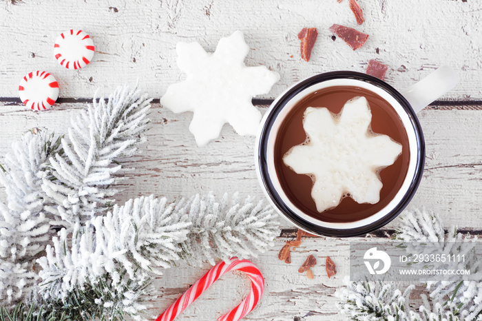 Hot chocolate with snowflake marshmallow. Top view table scene with snowy branches and candy against