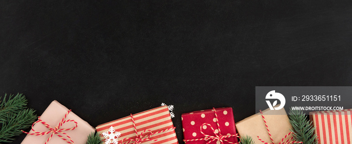 Gift boxes and Christmas ornaments on blackboard, banner background