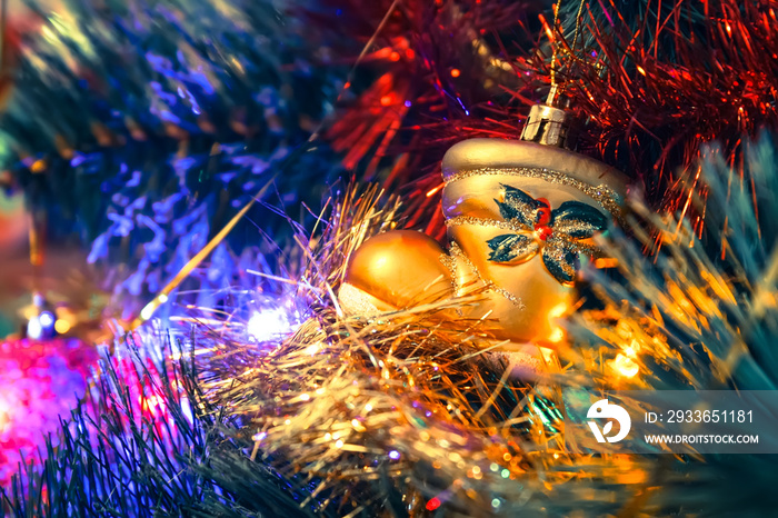 Golden boot toy hanging on a Christmas tree among the shiny garlands