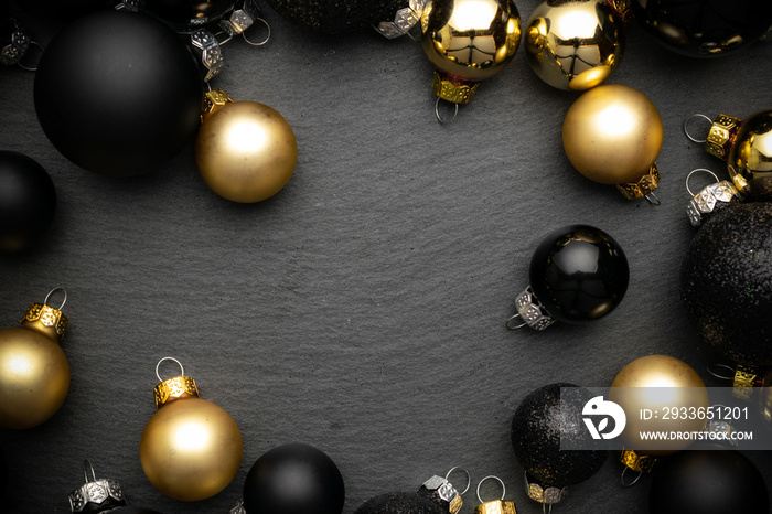 Gifts background. Gold Christmas baubles decoration on black textured background with copy space. Fl