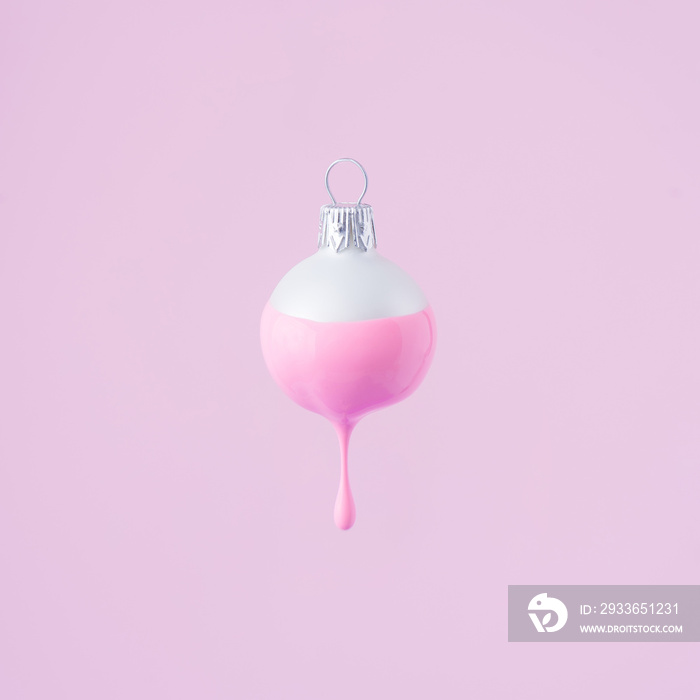 White Christmas bauble decoration with pastel pink paint dripping. Minimal New Year concept.