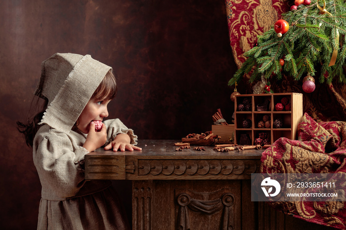 Little girl in an vintage linen dress near the table with sweets. Genre portrait in retro style.