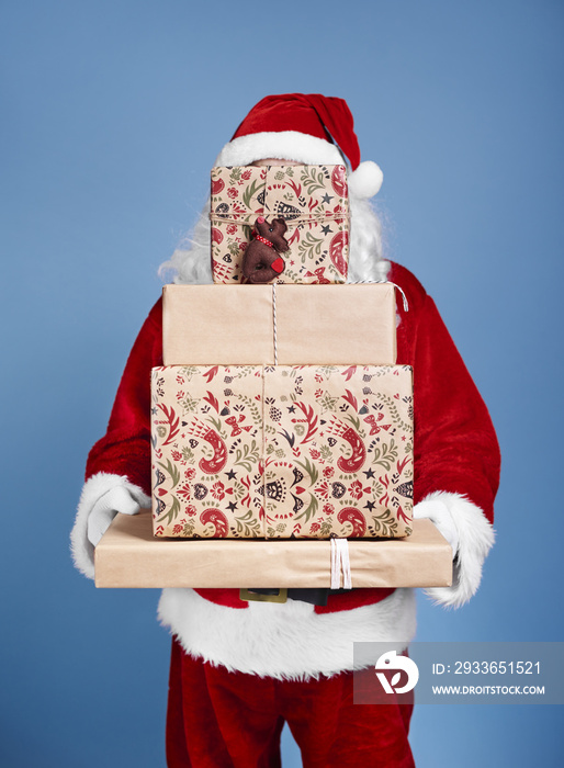 Santa Claus holding stack of christmas gifts