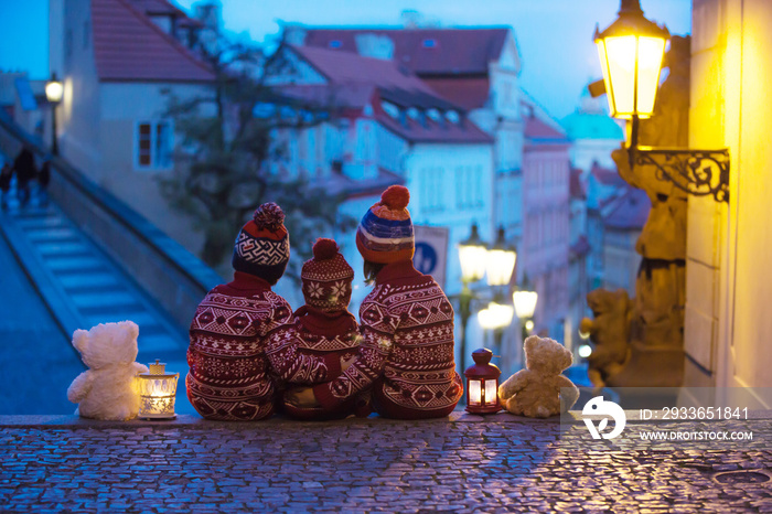 Beautiful children, three boy brothers, casually dressed, looking at night view of Prague city