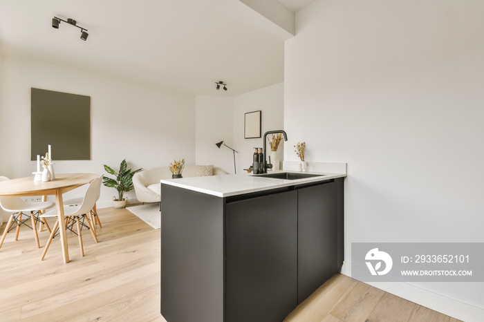 a kitchen and dining area in a house with white walls, hardwood flooring and black cabinetry on the 