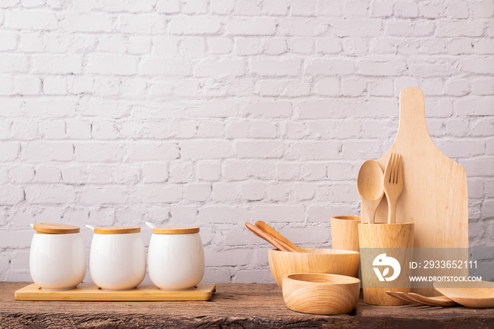 Kitchen table with wooden kitchenware set on brick wall texture background.