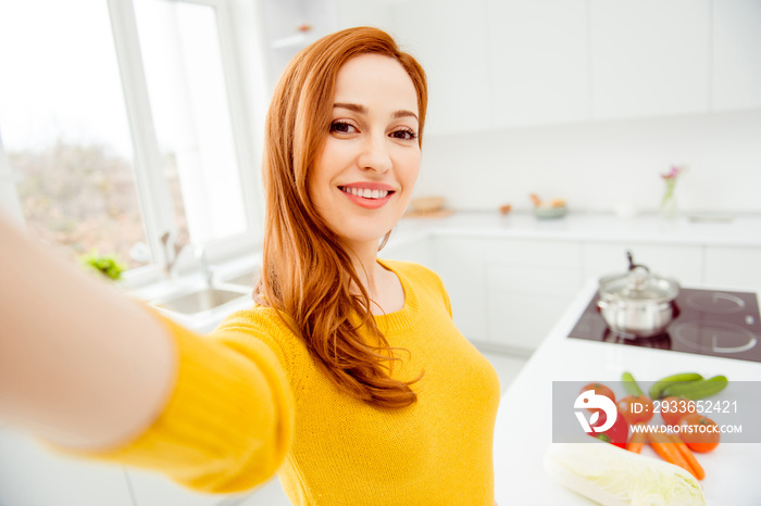 Young woman in yellow sweater make selfie on front camera of smartphone against tomato, cucumber, pe