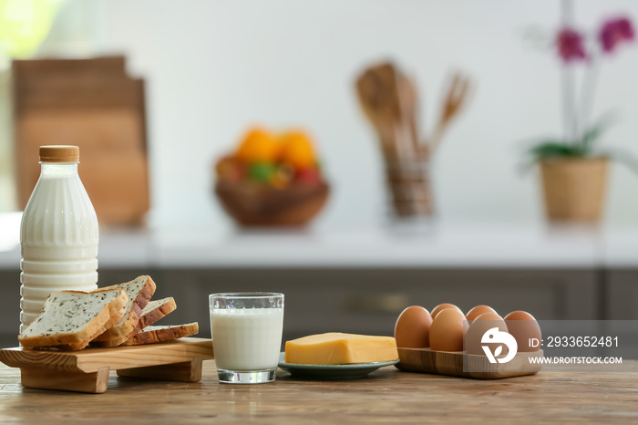 Glass of milk, cheese and toasts on table in modern kitchen