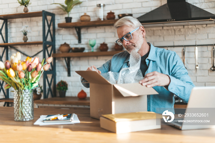 Open the parcel at home. An elderly man unpacks an online order. Feedback from buyers.