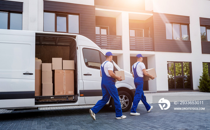 Two removal company workers unloading boxes from minibus into new home