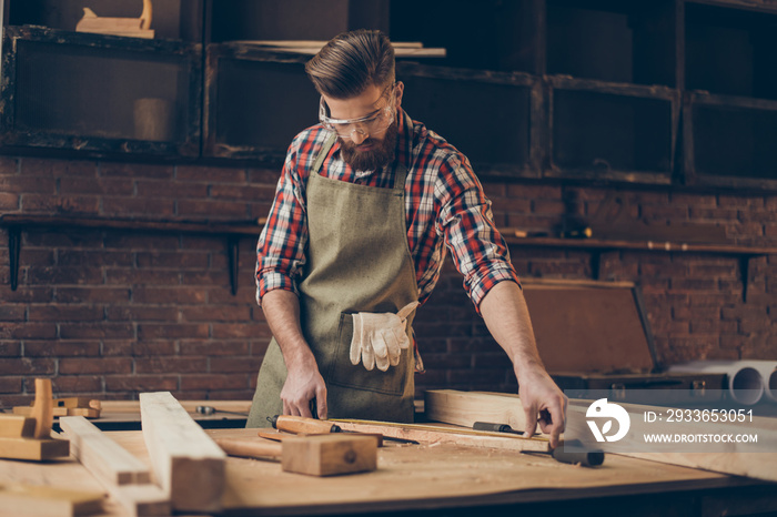 young stylish craftsman with glasses and hairstyle holding measuring tape near blank at tabletop in 