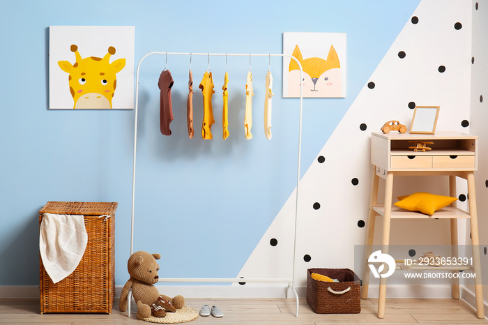 Interior of stylish childrens room with rack, baby bodysuits and table