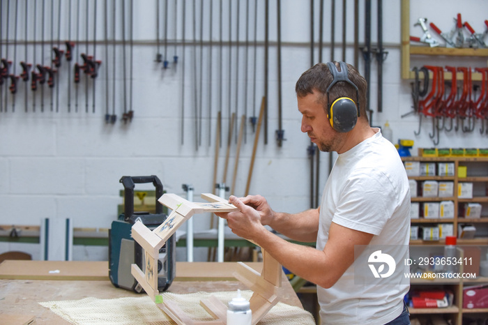 A man is making bespoke furniture in a woodwork workshop showing the construction process