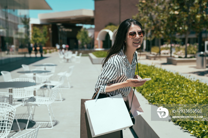 cheerful asian woman in fashion wear is turning around to look at camera with smiling face while sho