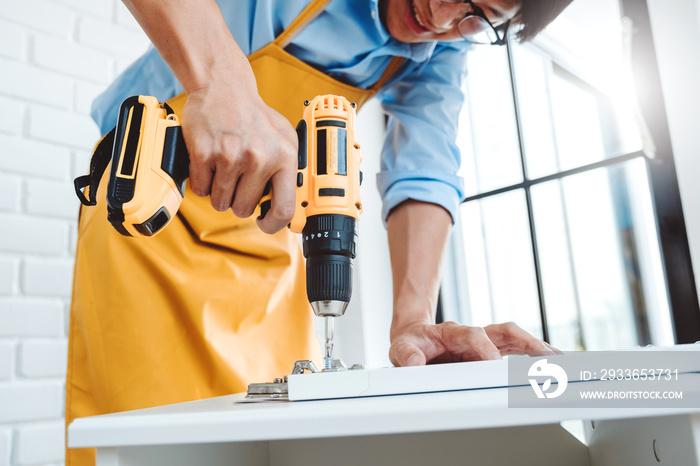 Happy asian man home improvement Assembling Furniture Reads Instructions and Tightens Screw with a D