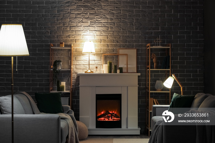 Interior of dark living room with fireplace, sofas and glowing lamps