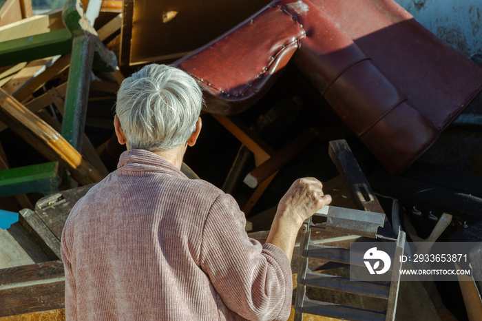 senior woman looking at a container full of old furniture