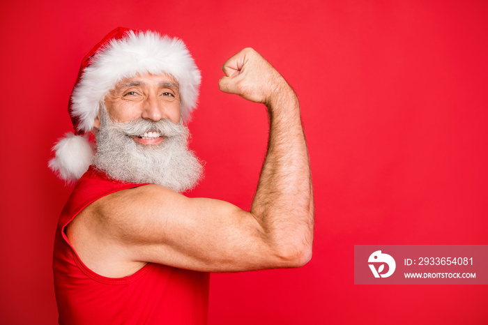 Close up photo of cheerful santa claus in hat cap with white hairstyle showing his biceps gymwearing