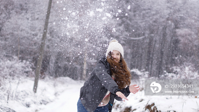 Happy young woman in a snowball fight. Winter holiday spirit.