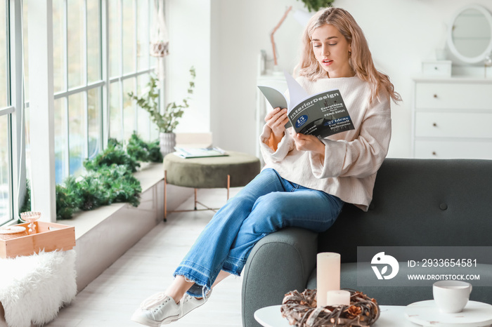 Beautiful young woman in warm sweater reading magazine at home