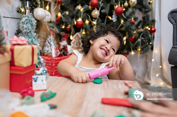 Happy Asian little girl have fun on Christmas day. Kid with parent with Christmas tree decoration at