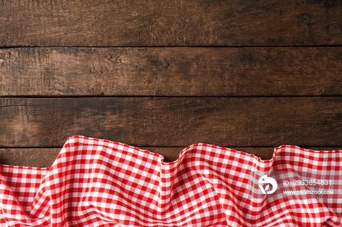 Red checkered tablecloth on wooden background with copyspace