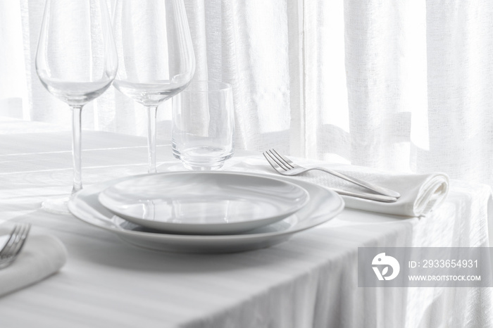 Table setting white and grey colour. Empty glasses and plates set with napkin and cutlery on white t