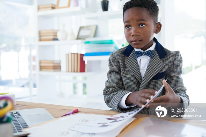 Businessman holding documents while sitting at desk