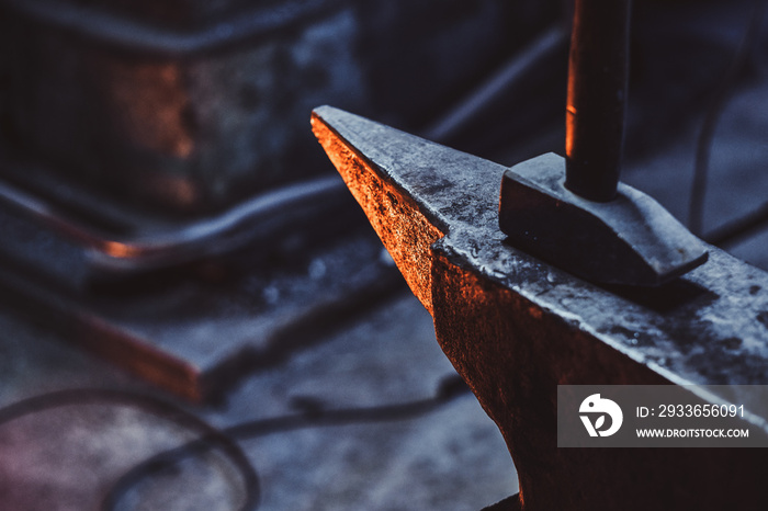 Close up photo shoot of hammer and anvil at dark smith workshop.