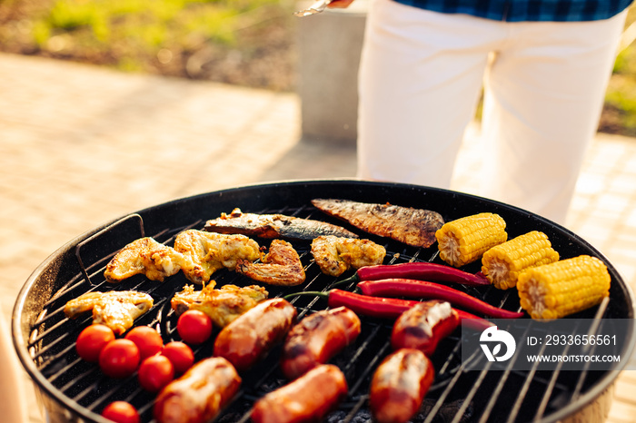 man prepares a barbecue for friends, happy friends make a barbecue outdoors at sunset, A man roasts 