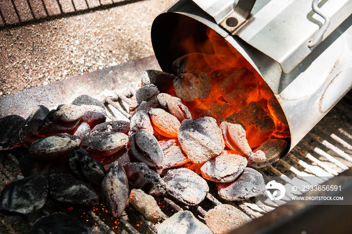 Glowing coals pouring from charcoal chimney starter