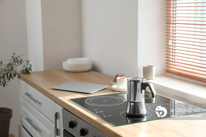 Geyser coffee maker on electric stove in kitchen near window