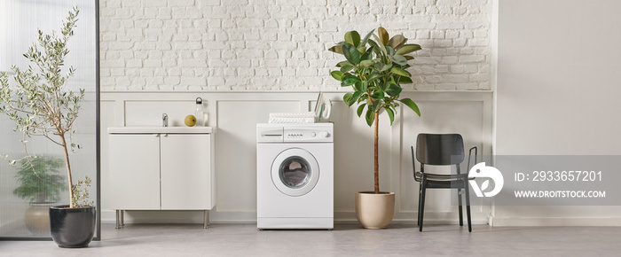 Washing machine in the bathroom, white brick wall background, vase of plant, cabinet and marble floo