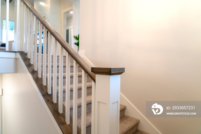 Indoor staircase of a home with white balusters brown handrail and newel