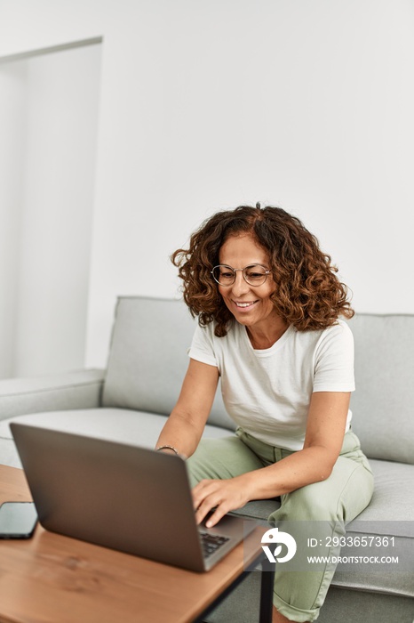 Middle age hispanic woman smiling confident using laptop at home