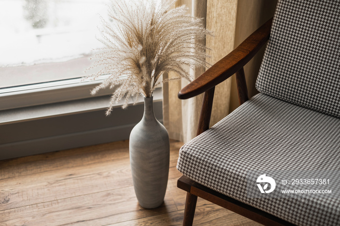 Mid-century retro chair and pampas grass bouquet in clay pot against window with curtains. Modern ae