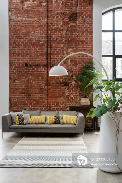 Interior of living room in loft apartment in industrial style. Comfortable sofa with pillows, modern