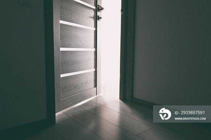 The light revealing through the half open wooden door in the house