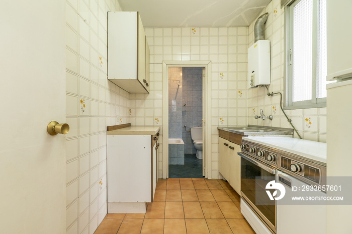 Old kitchen with old furniture in poor condition and access to a toilet in the same condition