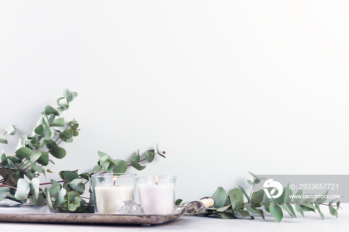 White room interior decor with burning white candle and greenery