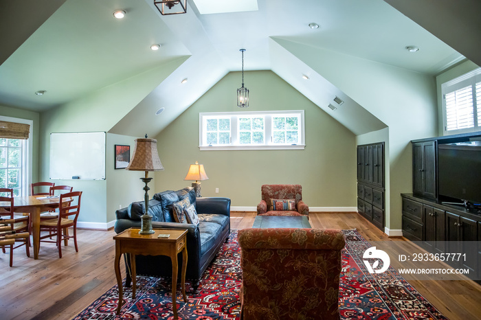 bonus room in an upstairs oft style area painted green with a comfortable couch and arched ceiling d