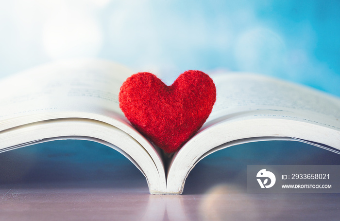 red heart in book or bible on wooden table, love concept.