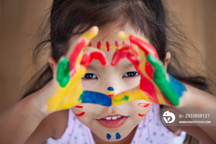 Cute asian little child girl with painted hands make heart shape colorful with fun and love